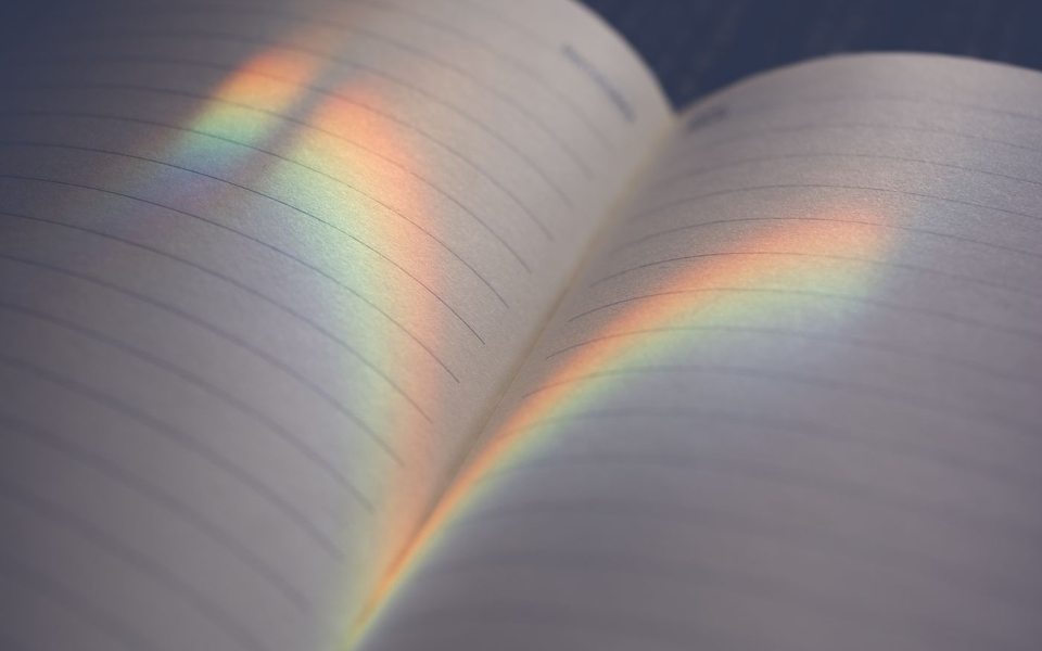 Soft rainbow light falling across the pages of an open notebook.